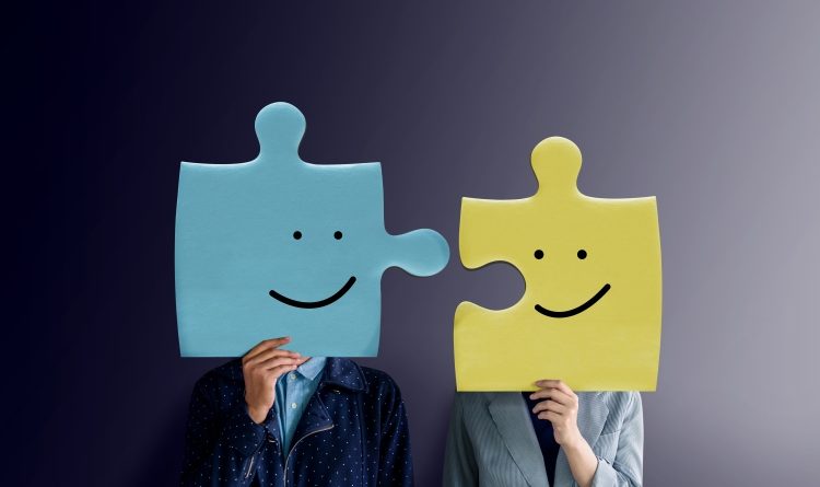 Two individuals holding jigsaw pieces with smiley faces.