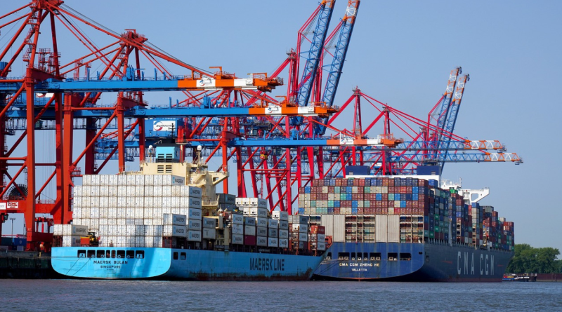 Container ships docked at a busy port with large cranes unloading cargo, highlighting global supply chain challenges.