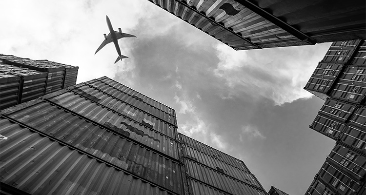 After 175 years of supply chain protection, Pinkerton’s approach still delivers continuity and resilience an airplane in the sky above large stacks of intermodal shipping containers