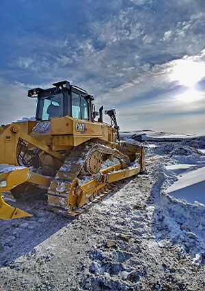 a large, yellow Caterpillar dozer in a snowy, outdoor working environmen