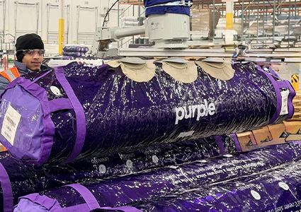 a Purple brand mattress, packaged for shipping in its signature rolled-up purple bag.