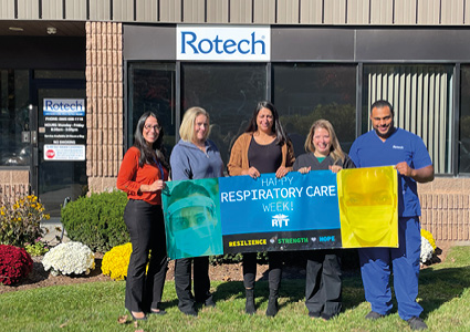 a group of people holding a banner in front of a building with the sign "Rotech" to celebrate Respiratory Care Week