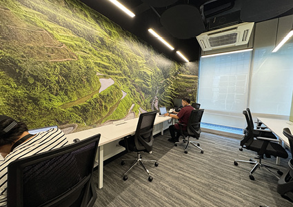 a modern office workspace featuring a large nature-themed mural on the wall and several desks with office chairs