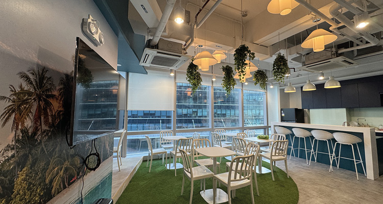 a breakout lounge area designed to resemble a contemporary garden with artificial turf, hanging plants, and a tropical mura