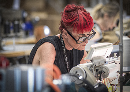 a person working diligently with a sewing machine in a garment production setting