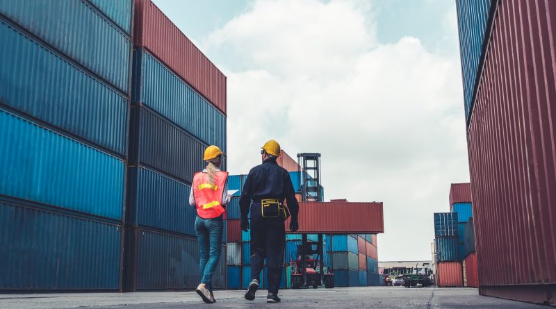 Supply chain professionals monitor logistics operations alongside AI-powered analytics and automation systems in a modern distribution environment.