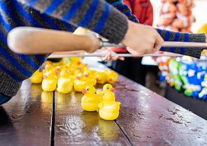 a close-up, side-angle view of someone playing a classic "hook-a-duck" game at a carnival or fairground