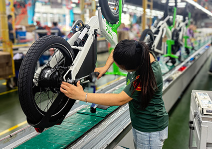 an assembly line worker meticulously installing or adjusting the rear wheel mechanism of an electric bicycle in a manufacturing facility