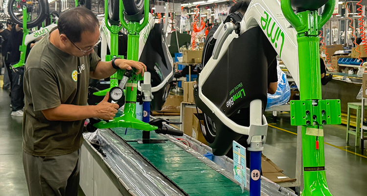 a factory worker assembling or quality-checking electric bicycles on an industrial production line