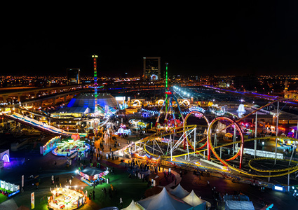 a high-angle aerial view captures a sprawling amusement park illuminated at night