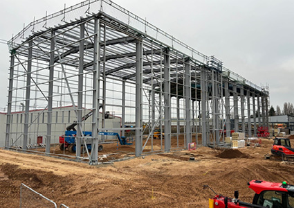a large industrial warehouse or commercial building in the early stages of construction under an overcast sky