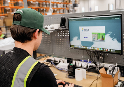 a warehouse employee working at a computer station within a large logistics facility