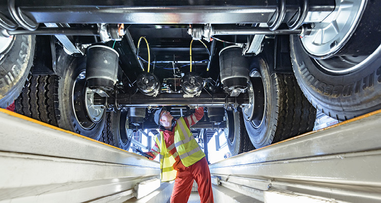 a mechanic inspecting the air suspension and axle undercarriage of a commercial heavy goods vehicle