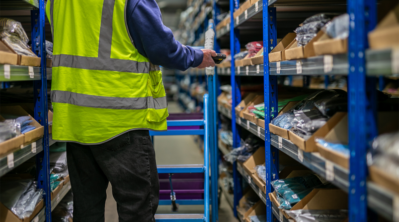 Logistics warehouse operative wearing a high-visibility yellow vest and using a wearable barcode scanner