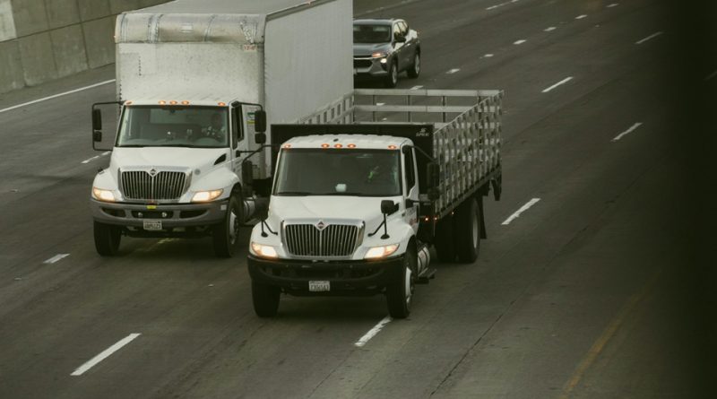 Commercial delivery trucks travelling on a highway, representing military power supply sourcing and logistics.